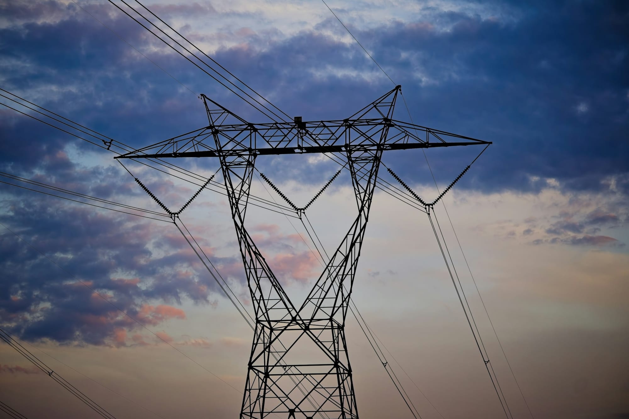 Electrical transmission tower silhouette against the sky