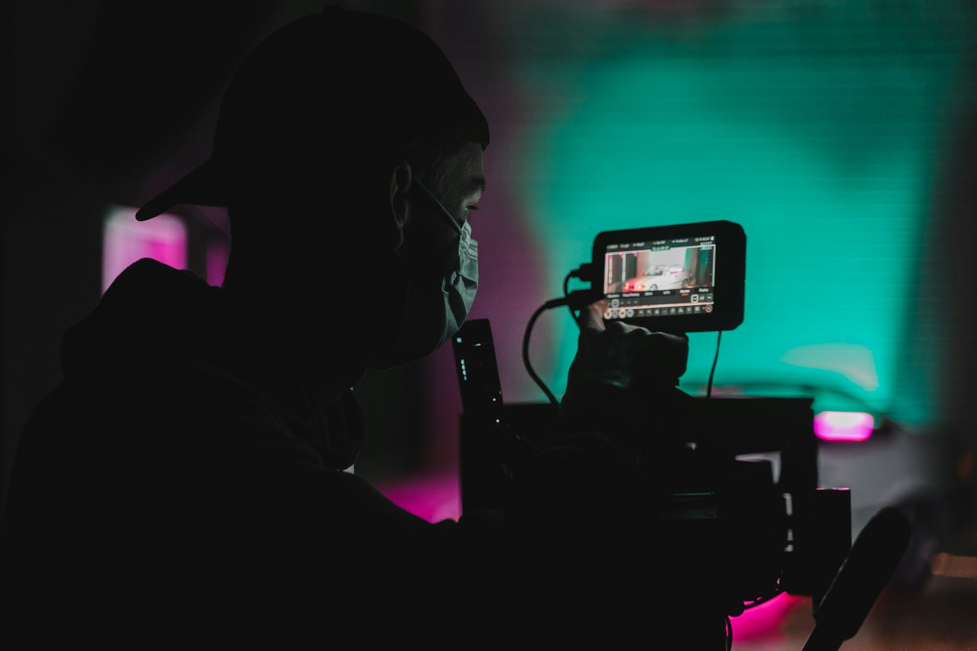 Camera operator reviewing footage on a monitor with colored gel lighting